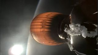 white frost-like material builds up around a cone-shaped rocket nozzle as it glows orange