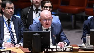 a bald man in a suit sits at a large wooden table behind a sign that reads "russian federation"